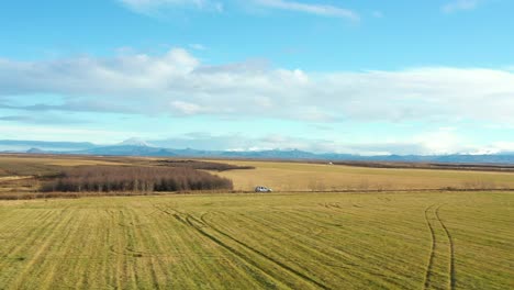 Aerial-pullback-follow-car-driving-on-countryside-road-on-Iceland-fields