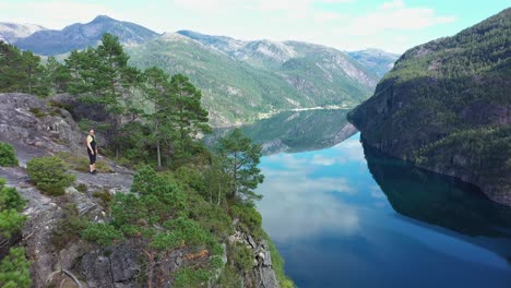 Frau-Steht-Am-Rand-Einer-Hohen-Klippe-Mit-Panoramablick-Auf-Den-Mo-Fjord-Und-Die-Faszinierende-Berglandschaft---Norwegen-Antenne