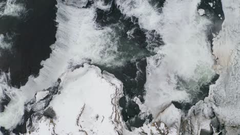 Aerial-tilt-up-shot-of-vast-Reykjafoss-Waterfall-during-snowy-day-in-Iceland
