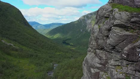 Gently-flying-close-to-cliff-with-beautiful-green-lush-valley-in-Background---Forward-moving-aerial-in-Oyadalen-Stamnes-Norway---Complete-wilderness
