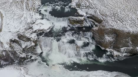 Filmische-Luftaufnahme-Von-Oben-Nach-Unten-Des-Atemberaubenden-Reykjafoss-wasserfalls-Während-Des-Frostigen-Wintertages-In-Island---Nach-Oben-Kippen