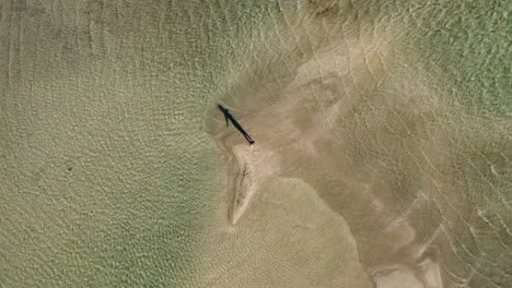 Drone-Ascendiendo-Con-Una-Mujer-Girando-En-La-Playa-De-Elafonissi-Durante-El-Verano-En-Creta,-Grecia