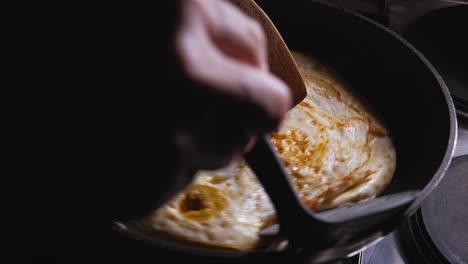 Person-folding-golden-savoury-cheese-toasted-tortilla-wrap-in-frying-pan