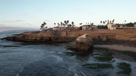 Aerial-view,-Pacific-Ocean-waves-breaking-on-coast-of-California-under-San-Diego-Cliffs-neighborhood,-drone-shot