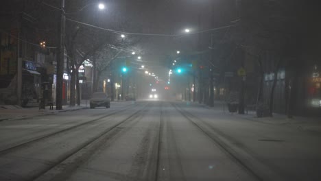 Glowing-Headlights-Of-Oncoming-Car-Driving-On-A-Snow-Covered-Road-In-Winter