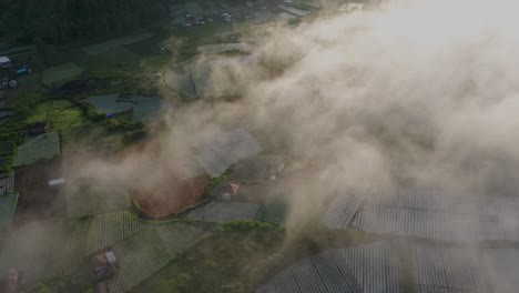 Niebla-Que-Fluye-Lentamente-Sobre-El-Pueblo-Rural-En-Bali-Con-Famosos-Campos-De-Arroz,-Antena