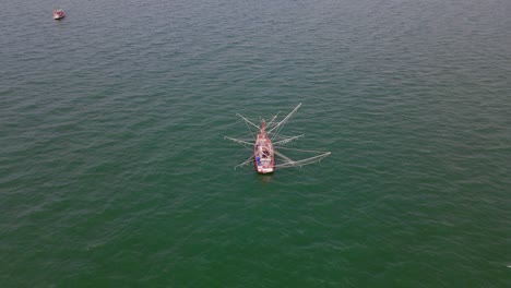 A-fishing-boat-and-one-on-the-left-top-corner-captured-in-a-descending-aerial-footage-in-the-middle-of-the-ocean-in-Chonburi,-Thailand
