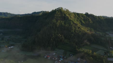 Tropical-lush-mountain-ridge-of-outer-ring-Batur-Caldera-during-sunrise,-aerial