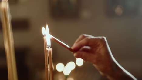 Religious-woman-lighting-up-a-candle-and-praying,-unrecognizable-person-practicing-their-beliefs,-close-up