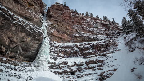 Time-lapse,-Frozen-Waterfall-and-Clouds-Moving-Above-Cliff-in-a-Cold-White-Snowy-Winter-Landscape-of-Outay,-Colorado-USA