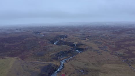 Toma-Aérea-Hacia-Atrás-Del-Profundo-Río-Selá-Flotando-En-La-Bahía-De-Hrútafjörður-En-El-Norte-De-Islandia-Durante-El-Místico-Día-De-Niebla
