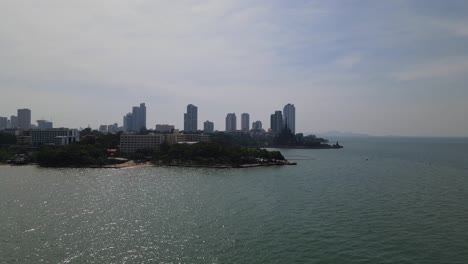 Ascending-aerial-footage-of-a-beachfront-hotel-and-the-Sanctuary-of-Truth-also-the-buildings-at-the-background-in-Pattaya,-Chonburi,-Thailand