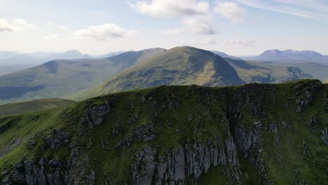 A-Male-standing-on-the-top-of-green-mountain-ridge-Fannichs-between-the-peaks-of-the-Scottish-highlands-on-a-sunny-day