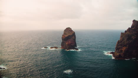 High-cliffs-with-rock-in-sea-on-coast-of-Madeira-Island-at-Ponta-de-Sao-Lourenco,-Portugal---aerial-static