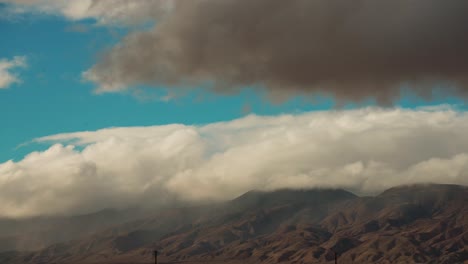 Der-Wind-Schiebt-Schnee-Und-Regenwolken-Rollen-Gegen-Die-Berge-In-Der-Mojave-wüste,-Während-Sich-Ein-Sturm-Nähert---Zeitraffer