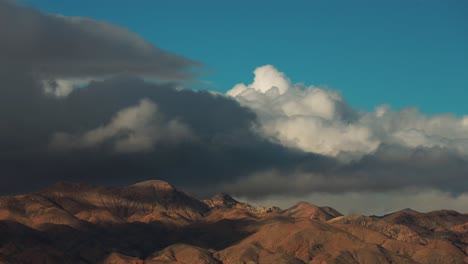 Mountains-on-the-borders-of-the-Mojave-Desert-with-fast-moving-storm-clouds-forming-and-rolling-over-the-rugged-peaks---time-lapse