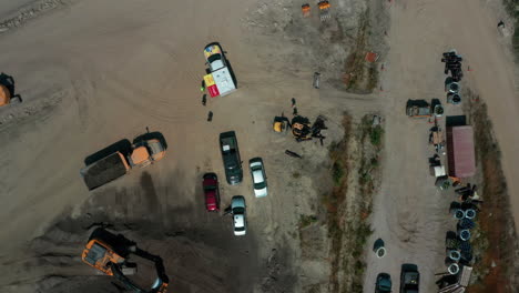 Aerial-view-rising-over-vehicles-and-heavy-equipment-at-a-contruction-site