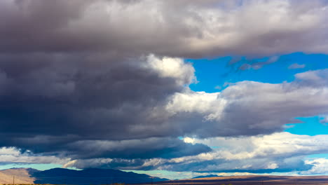 Huge-dark-clouds-rolling-across-the-Mojave-Desert's-rugged-landscape-threatening-rain---time-lapse