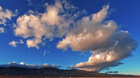 Riesige-Wolkenlandschaft,-Die-über-Die-Mojave-Wüste-Rollt,-Mit-Autos,-Die-Entlang-Der-Autobahn-Am-Fuße-Der-Berge-Fahren---Zeitraffer