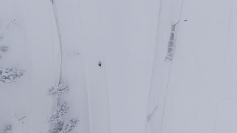 Person-enjoys-winter-while-skiing-on-track,-aerial-high-altitude-top-down-shot