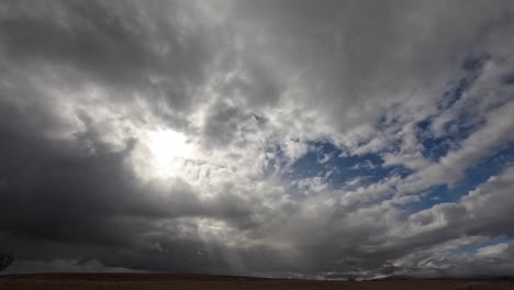 The-sun-peeks-and-shines-through-the-overcast-sky-above-the-Mojave-Desert's-endless-wilderness---wide-angle-time-lapse