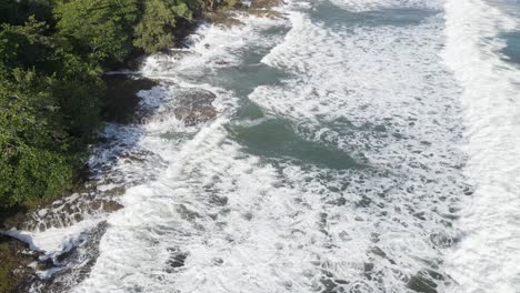 Birds-eye-of-ocean-waves-with-green-forest-and-jungle