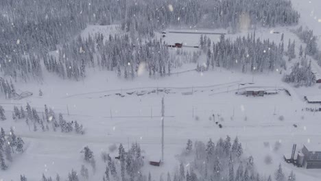 Cross-country-skiing-track-in-small-town-of-Sweden-during-snowfall,-aerial-drone-view