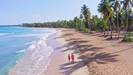 Couple-in-swimwear-walking-together-on-tropical-Caribbean-beach