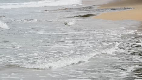 Close-up-shot-of-small-waves-crashing-ashore-at-the-Caribbean-sea-on-a-cloudy-afternoon