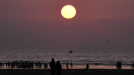 Gelbe-Sonne-Mit-Sonnenuntergang-Und-Silhouette-Von-Menschen-Am-Karachi-Beach-Zu-Fuß-In-Der-Ferne