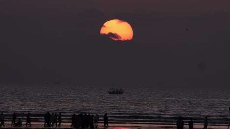 Orange-Sonne-Und-Sonnenuntergang-Himmel-Zoomen-Langsam-Heraus-Enthüllen-Die-Silhouette-Von-Menschen-Am-Karachi-Beach