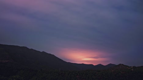 Timelapse-of-clouds-moving-at-night,-with-mountain-silhouette