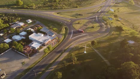 Aerial-shot-showing-red-truck-driving-in-roundabout-during-sunset-light-in-Uruguay