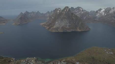 Aerial-view-overlooking-the-Reinefjord-and-mountains,-in-Lofoten,-Norway---tracking,-drone-shot