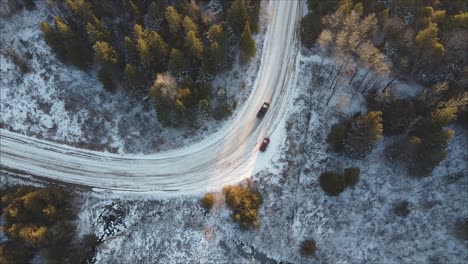 Top-Down-Shot-Of-A-Pickup-Truck-Driving-Past-A-Parked-Car-On-Forest-Road-During-Winter
