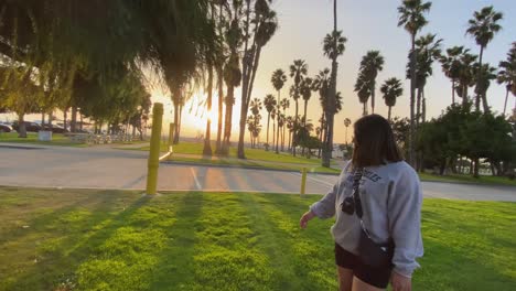 Girl-walking-at-Santa-Monica-Venice-beach-during-golden-hour-with-beautiful-Californian-Palm-trees