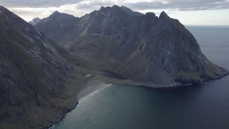Aerial-view-a-massive-mountain-ridge,-in-cloudy-Lofoten,-Norway---rising,-drone-shot