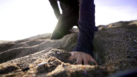 Close-up-exhausted-man-falling-with-his-hand-on-beach-sand