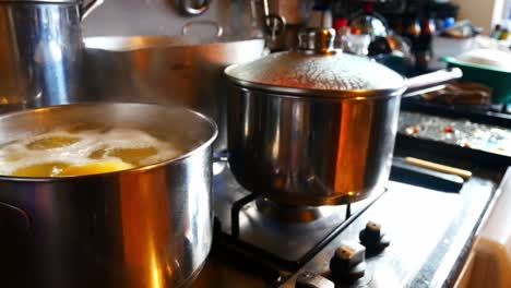 Silver-pots-cooking-Christmas-food-on-hot-gas-stove-in-family-kitchen-preparing-dinner-pull-back-left