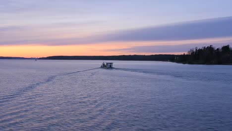 Filmischer-Blick-Auf-Ein-Motorboot,-Das-Bei-Einem-Wunderschönen-Orangefarbenen-Sonnenuntergang-Durch-Ruhige-Gewässer-Navigiert