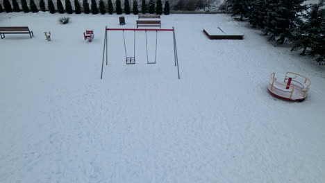 Empty-Swing-And-Benches-On-Snow-covered-Playground-During-Winter-Season-In-Lubawa,-Poland