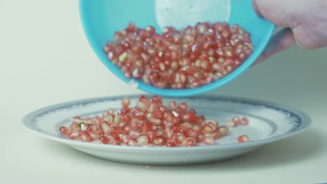 Pomegranate-seeds-pouring-out-of-bowl-onto-plate