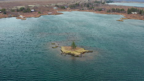 Tree-in-an-island-in-the-middle-of-a-scenic-water-body,-aerial-landscape-in-Thingvellir-national-park
