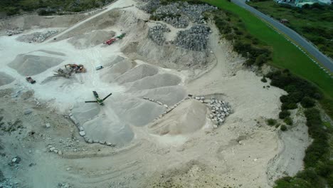 Heavy-machinery-in-gravel-quarry-dig-site,-aerial-drone-view