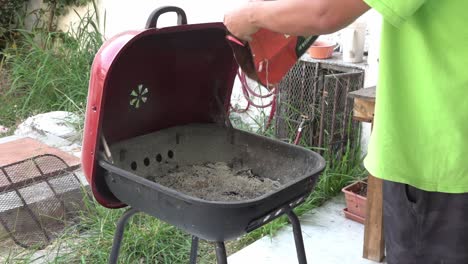 A-man-pouring-charcoal-briquettes-in-a-grill