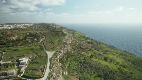 AERIAL:-Farmland-and-Road-On-Dingli-Cliffs-with-Blue-Mediterranean-Sea-and-Clear-Sky-in-Winter