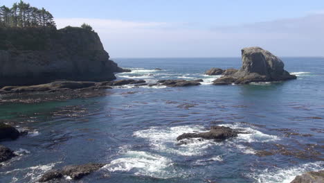 Pacific-ocean-waves-wash-over-low-rocky-islets-near-inlet-kelp-beds