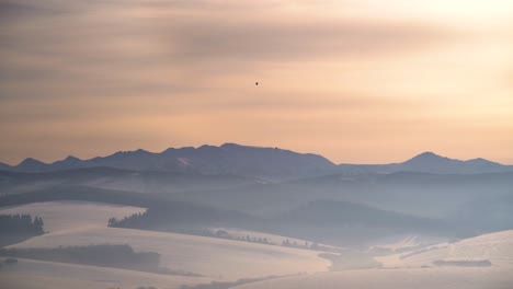 Ein-Einziger-Luftballon-über-Einer-Unglaublichen,-Silhouettierten-Winterberglandschaft-Bei-Sonnenuntergang