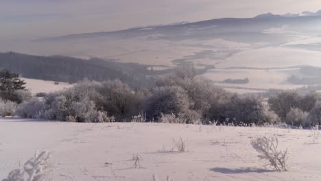 Tilt-up-over-frozen-winter-landscape-towards-mountain-range-in-distance