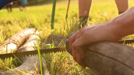Hand-Saws-A-Log-Outdoors-During-Summer-Scout-Camp,-Close-Up-Slow-motion